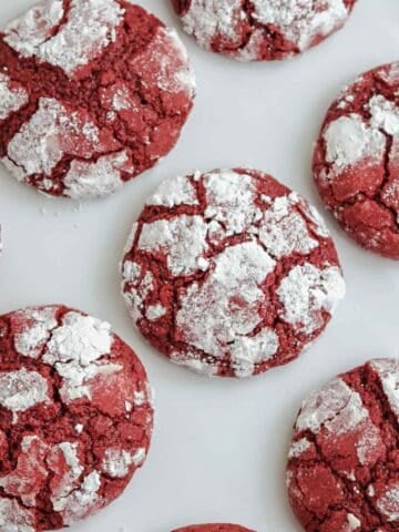 several red velvet crinkle cookies on a white background.