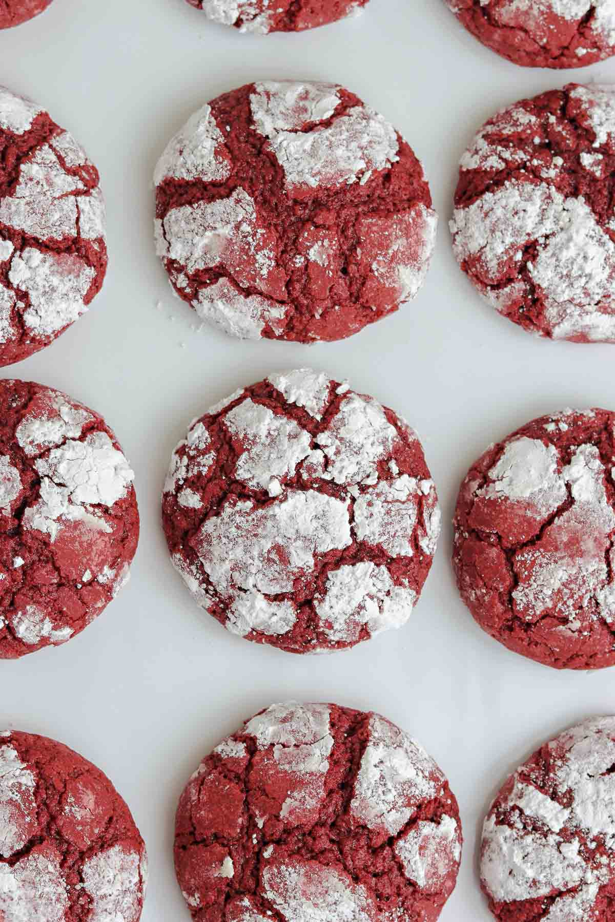 closeup of red velvet crinkle cookies on a white cutting board.