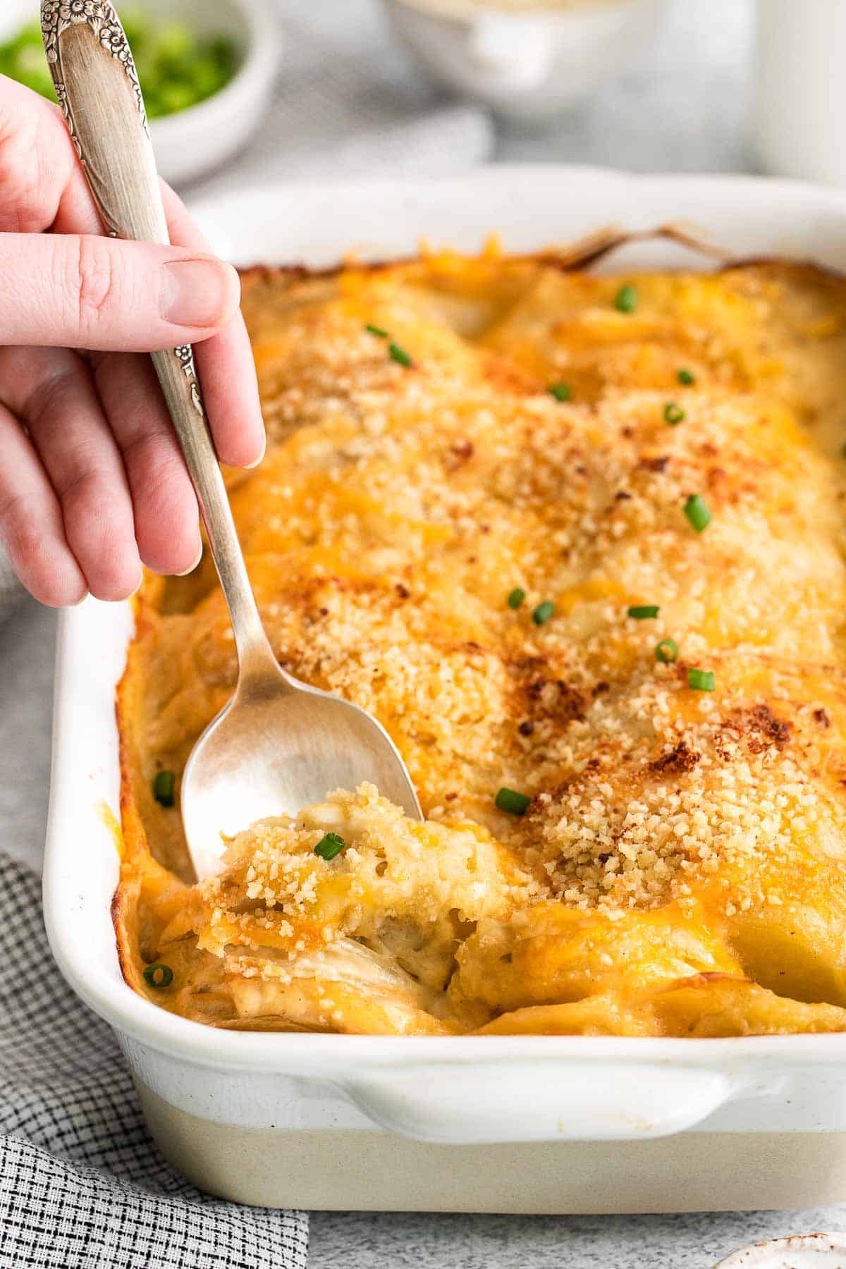 spoon scooped into a casserole dish of scalloped potatoes.