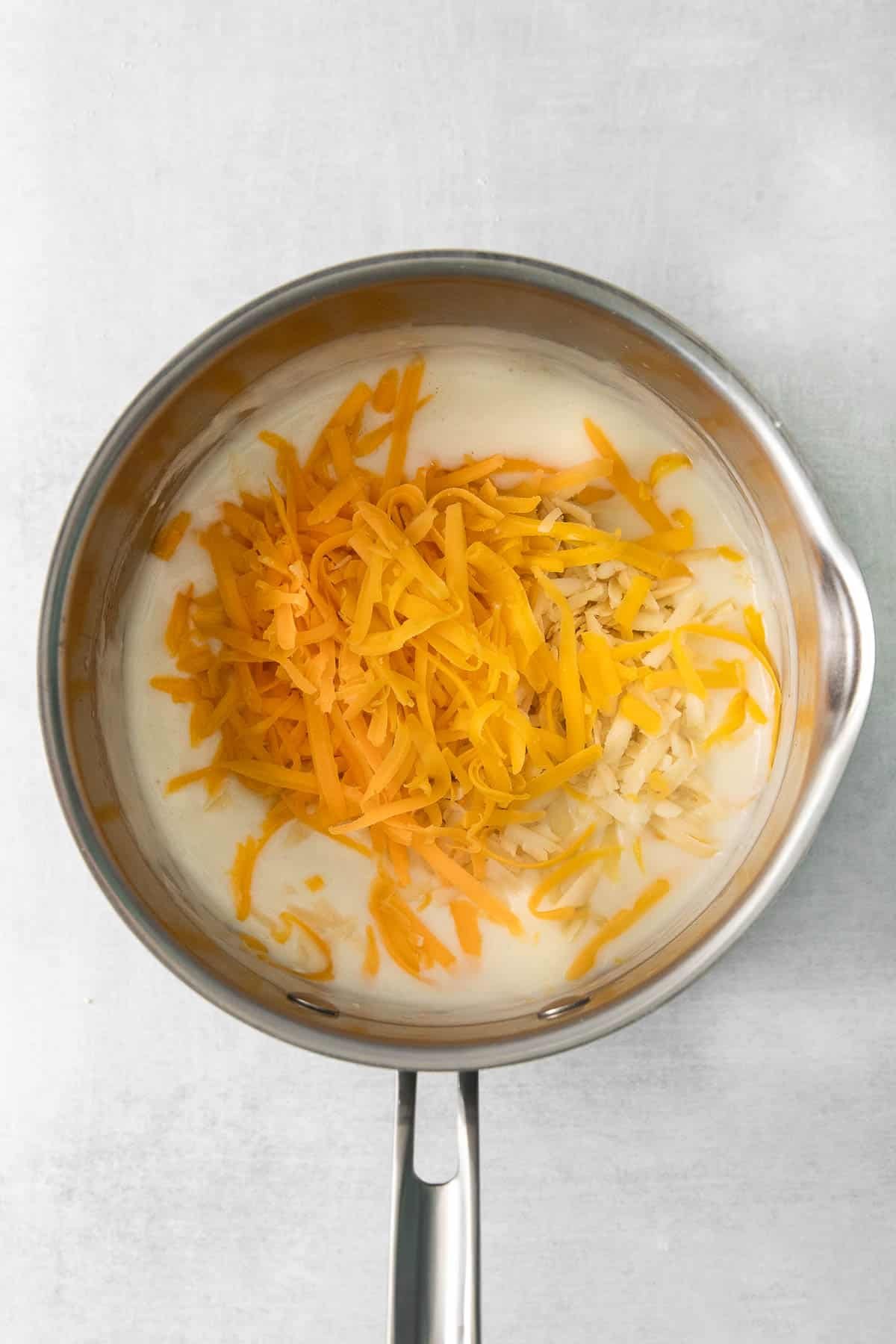 stainless steel pan with roux and shredded cheese.