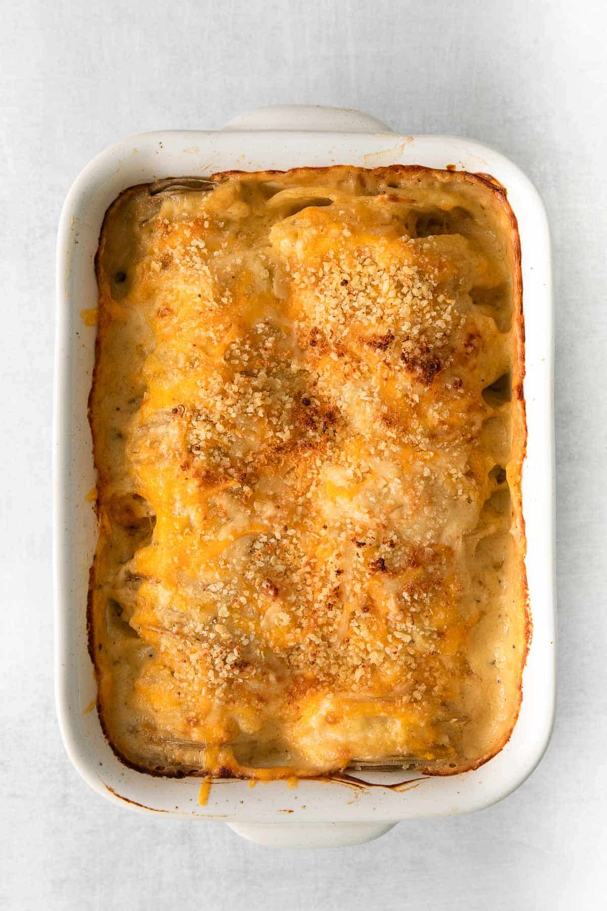 white casserole dish with cheesy topped scalloped potatoes.