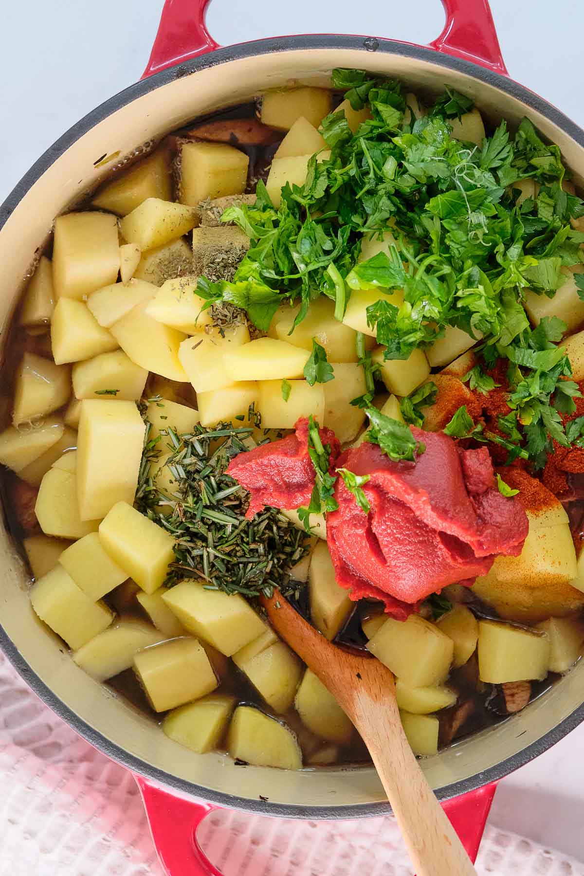 large soup pot with diced potatoes, tomato paste, parsley and spices.