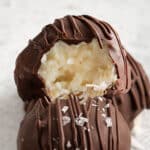 closeup of three chocolate covered coconut balls with one with bite taken out of