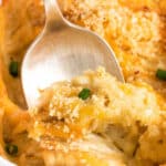 closeup of scalloped potatoes being scooped out of a white baking dish.