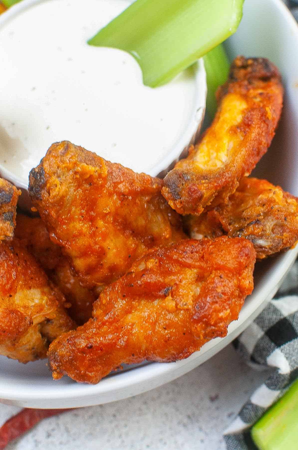 closeup of buffalo chicken wings in a white bowl.