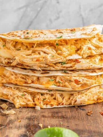 a stack of four buffalo chicken quesadillas on a cutting board.