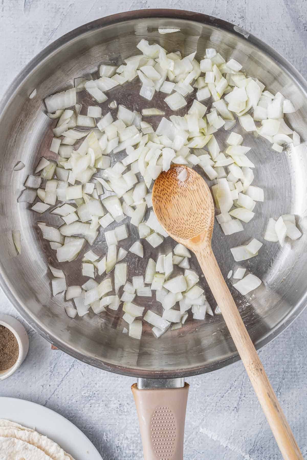 stainless steel skillet with raw diced onions.