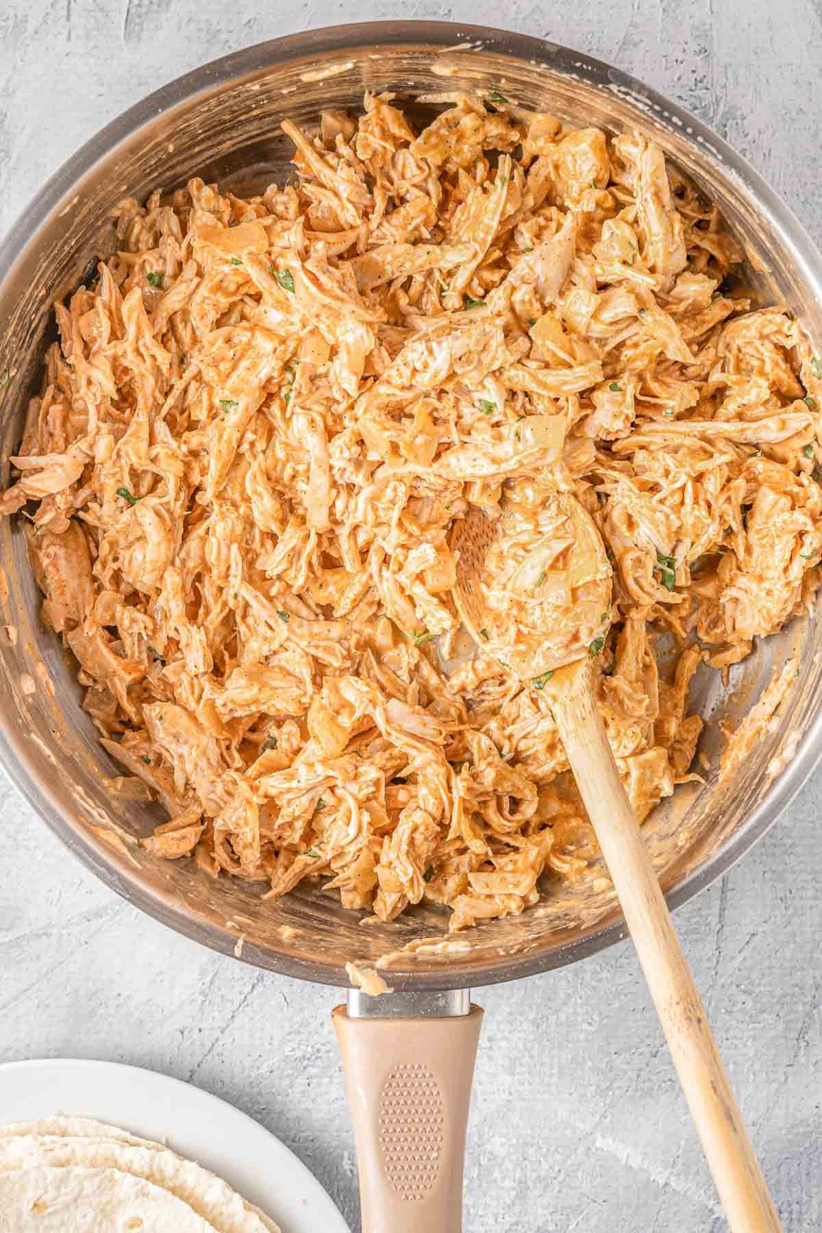 stainless steel skillet with shredded buffalo chicken.