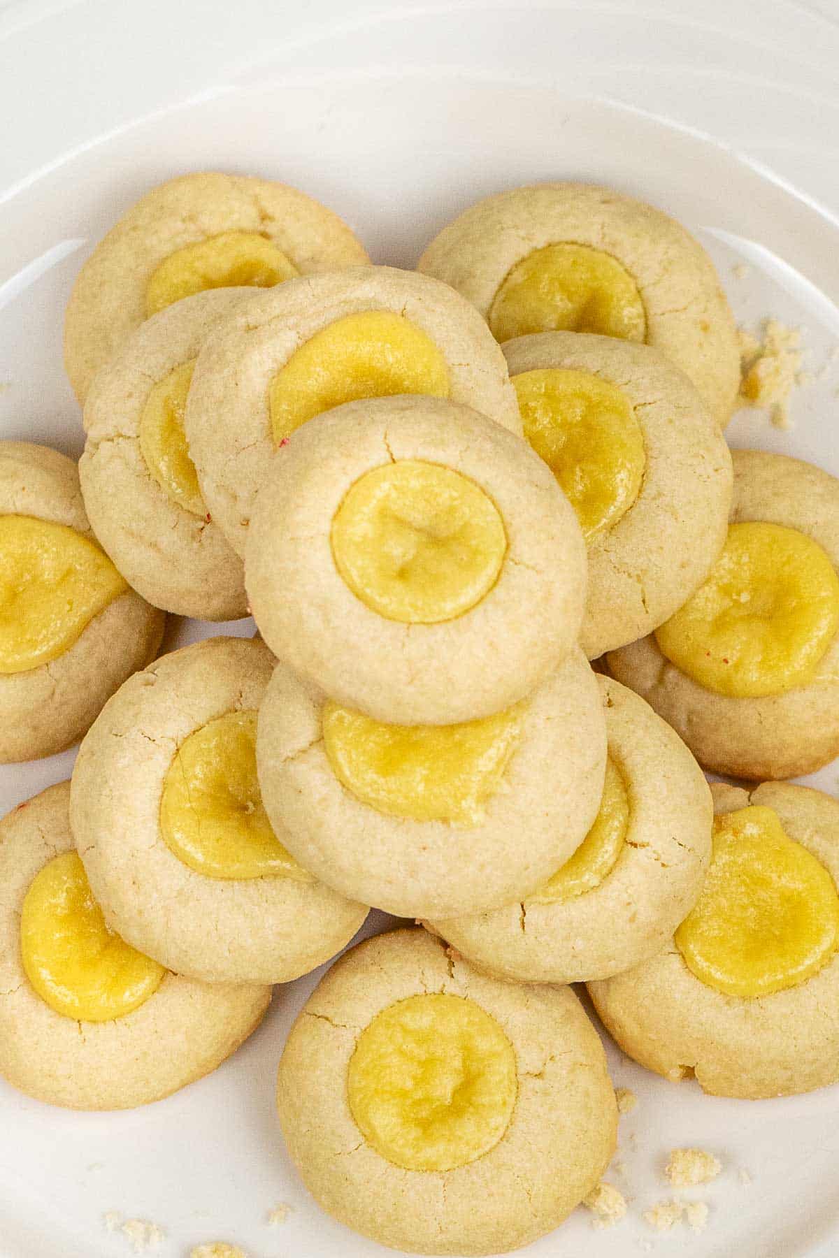 a stack of cheesecake thumbprint cookies on a white plate.