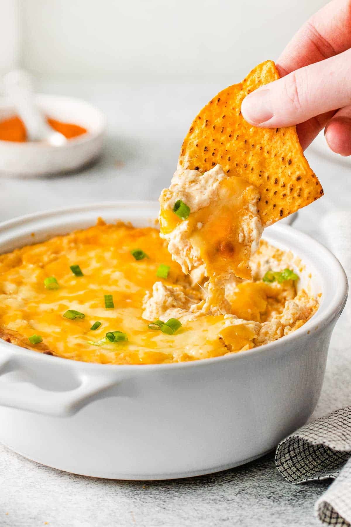 closeup of a chip full of hot cheesy crab dip on a tortilla chip.