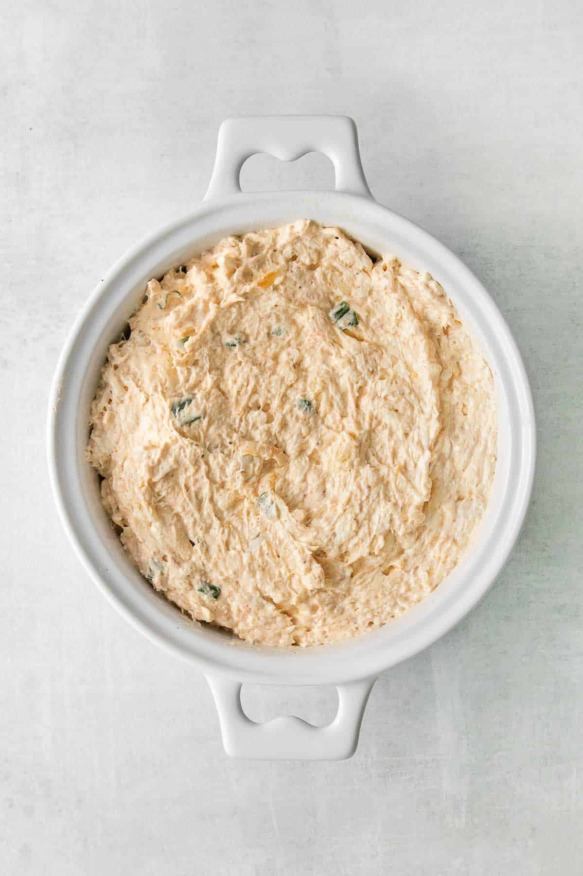 white baking dish with cheese and crab dip mixture.