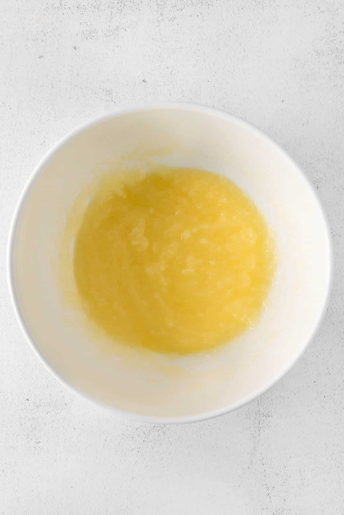 white bowl with sugar, melted butter and oil mixed together.