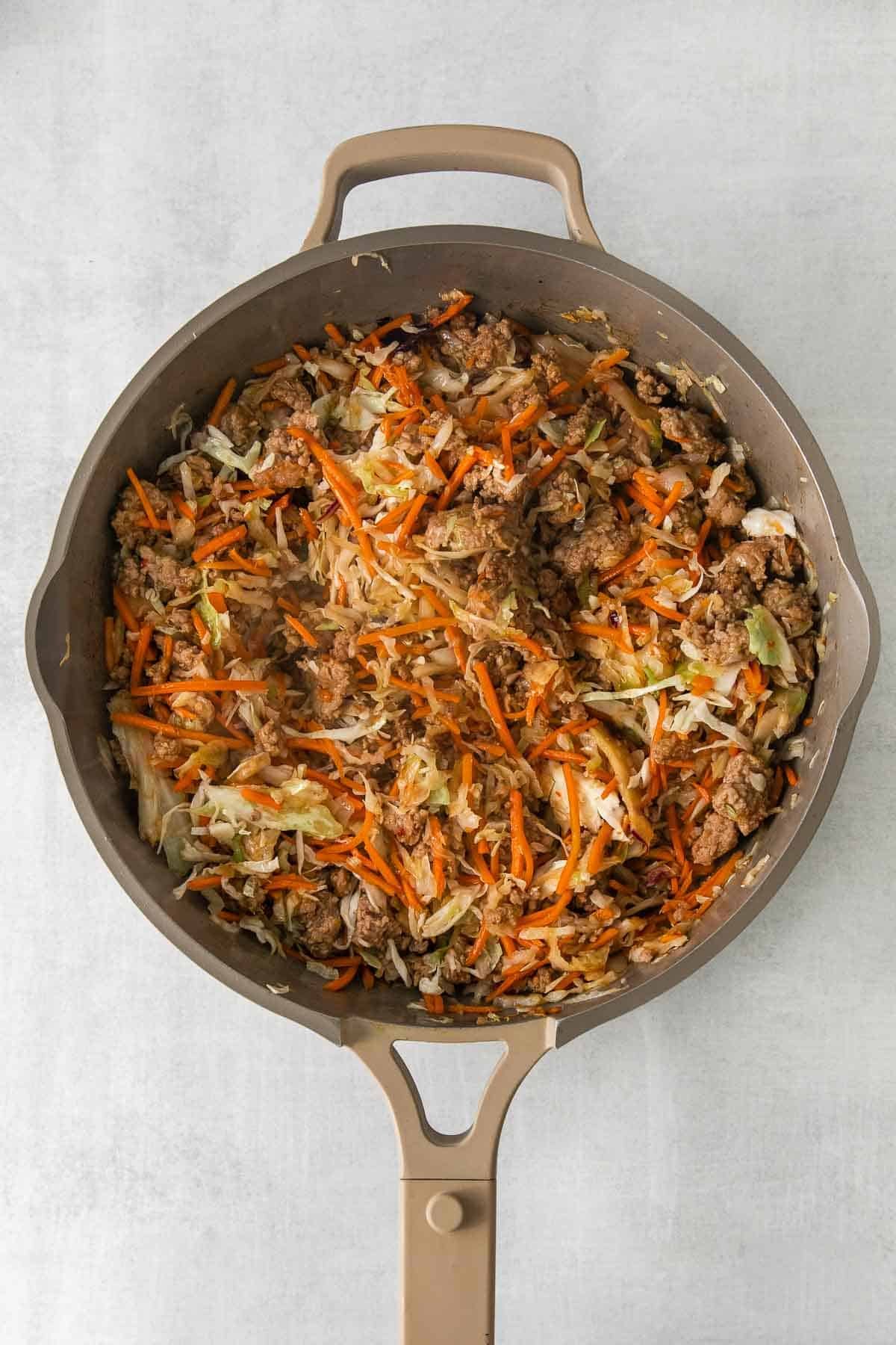 tan skillet with ground meat, shredded cabbage and carrots.