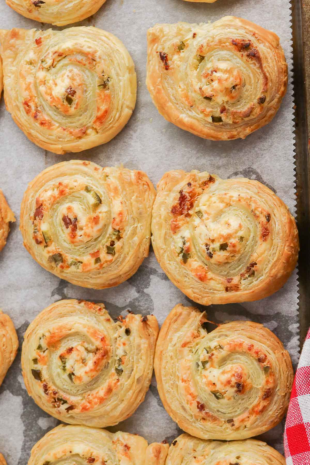 several jalapeno popper pinwheels on a baking sheet lined with parchment paper.