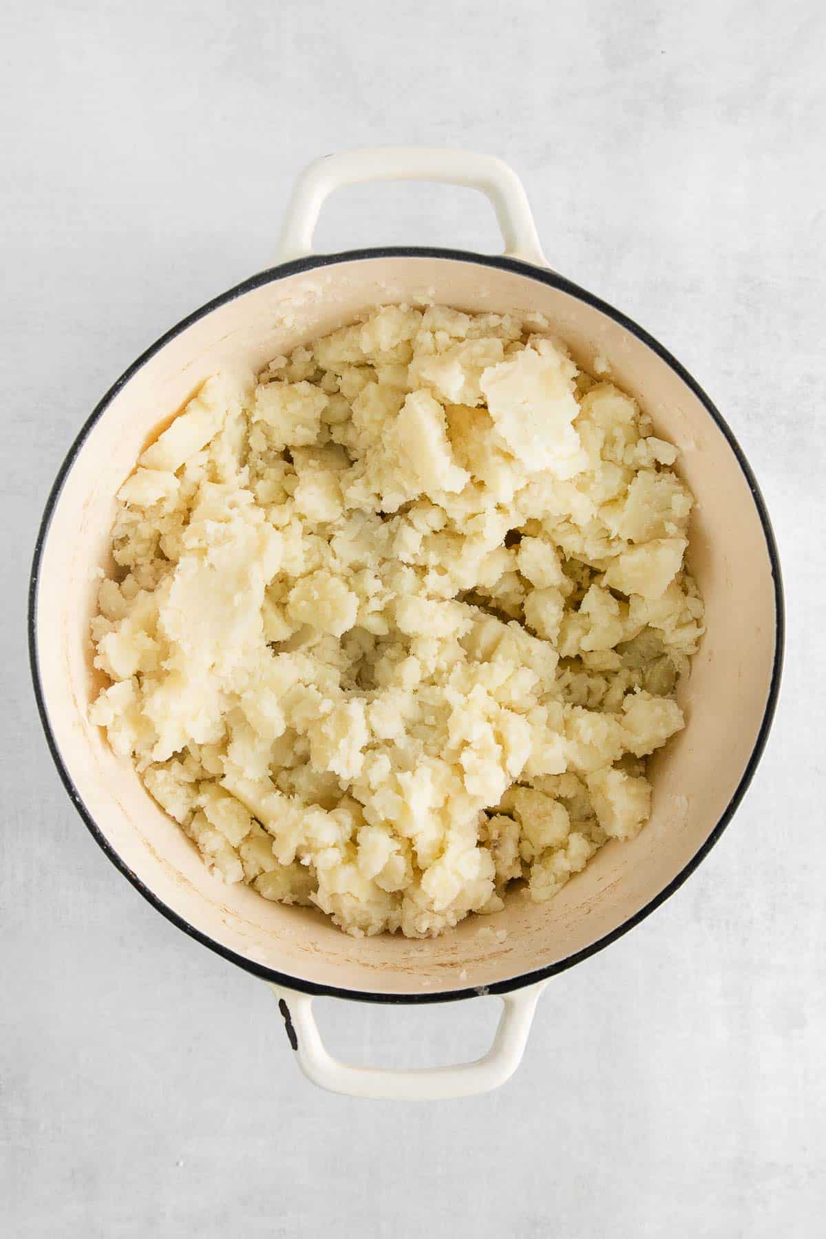 slightly mashed potatoes in a big white pot.