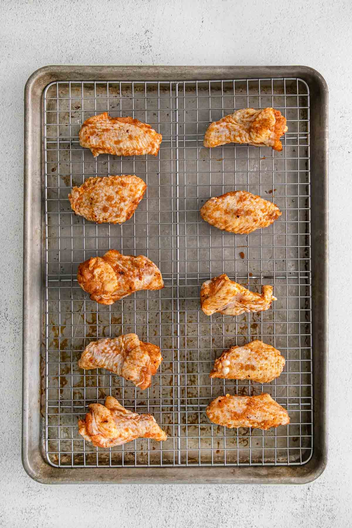 ten raw chicken wings on a wire rack in a baking sheet.