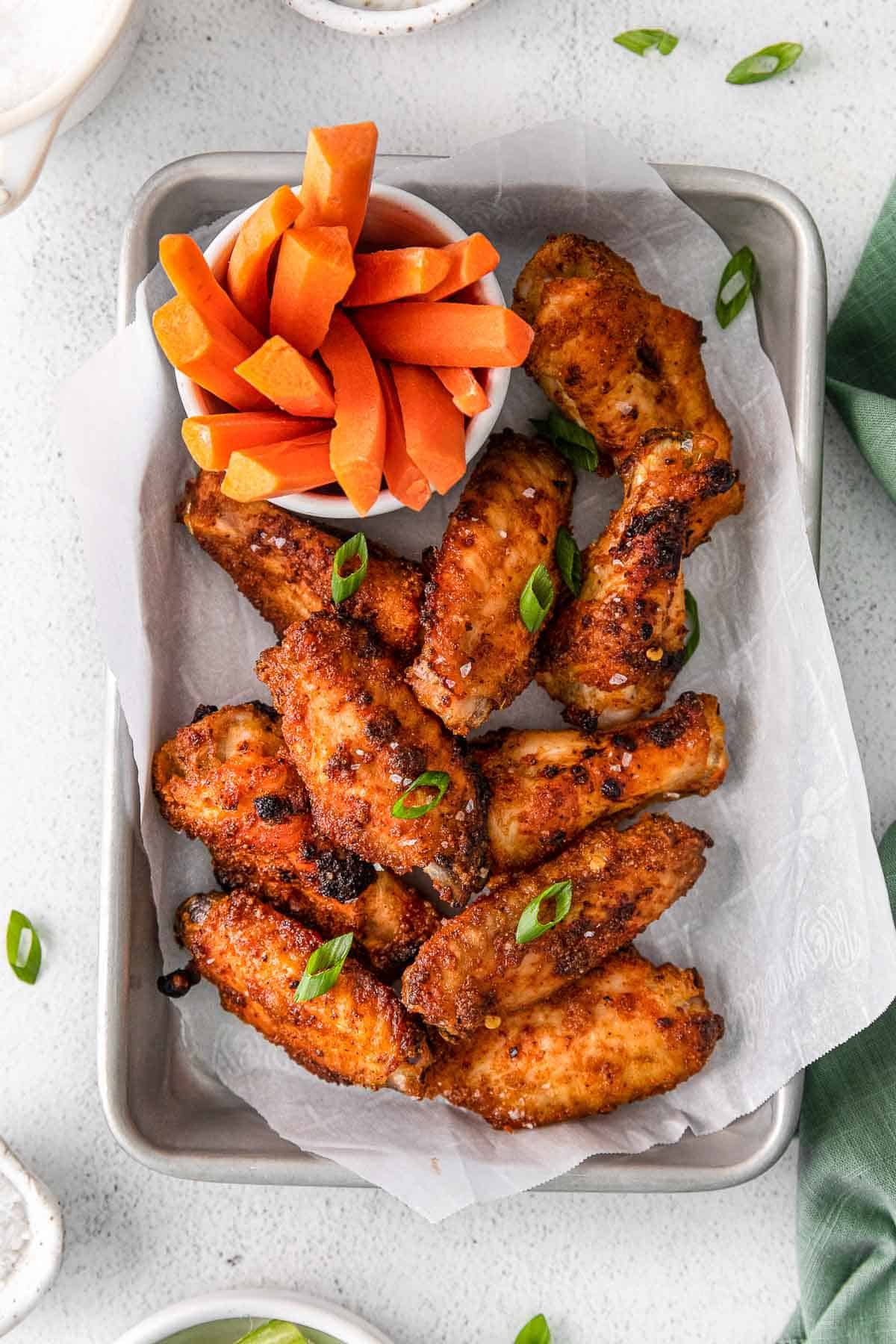 several crispy chicken wings on white parchment lined pan.