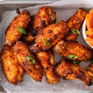 closeup of several crispy chicken wings on white parchment paper.