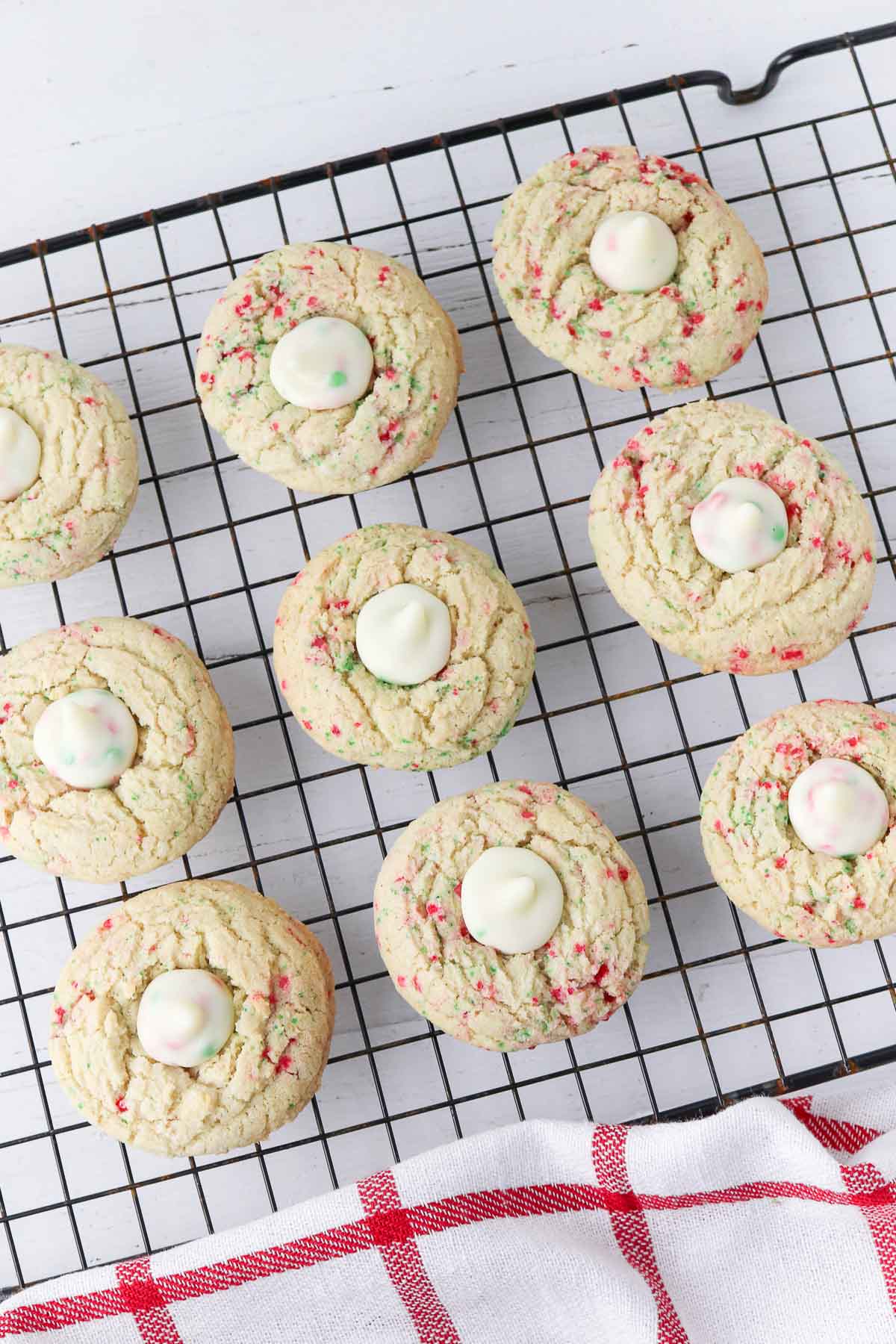 nine sugar cookie blossom cookies baked with red and green sugar sprinkles and a white chocolate Hershey kiss in the center.