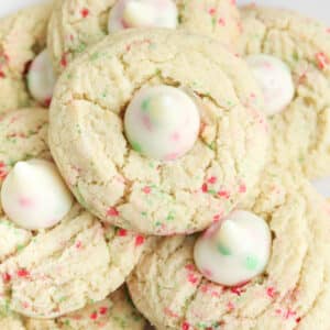 closeup of a sugar cookie with red and green sprinkles baked in and a sugar cookie hershey's kiss in the center.