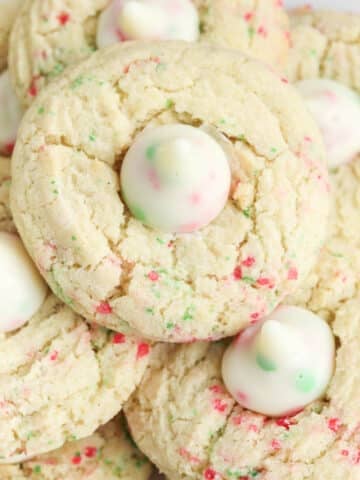 closeup of a sugar cookie with red and green sprinkles baked in and a sugar cookie hershey's kiss in the center.