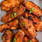 several crispy baked chicken wings on white parchment paper.
