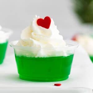 closeup of grinch jello shot with whipped cream and a red candy heart.