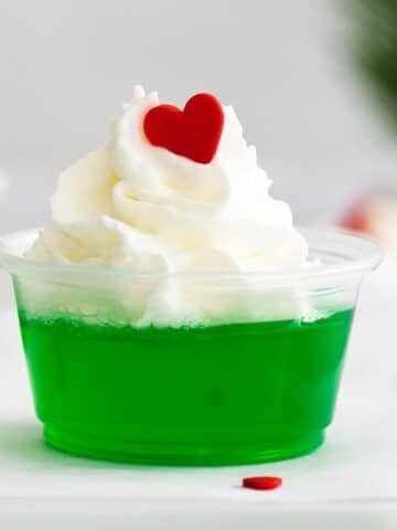 closeup of grinch jello shot with whipped cream and a red candy heart.