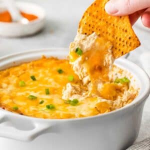 closeup of cheesy hot crab dip being scooped with a tortilla chip.