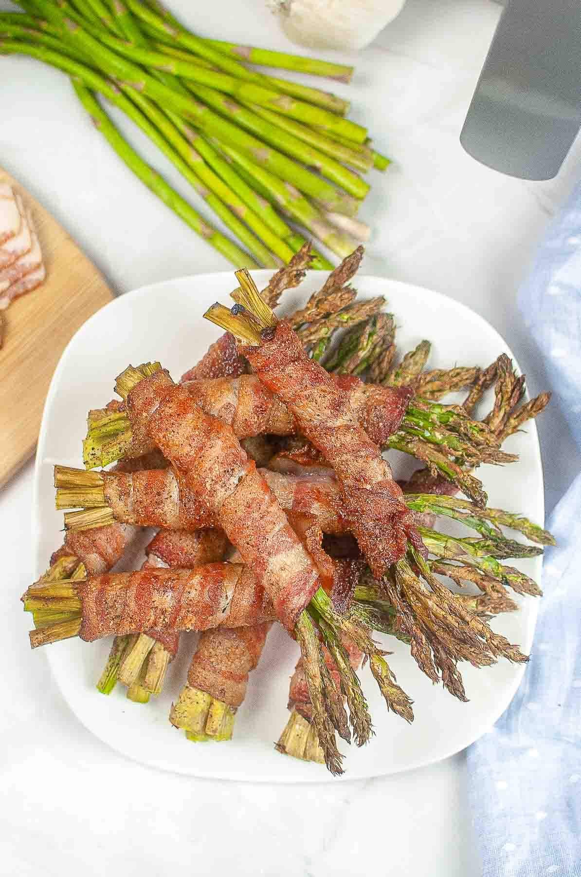 white plate with several small bundles of asparagus wrapped in bacon.