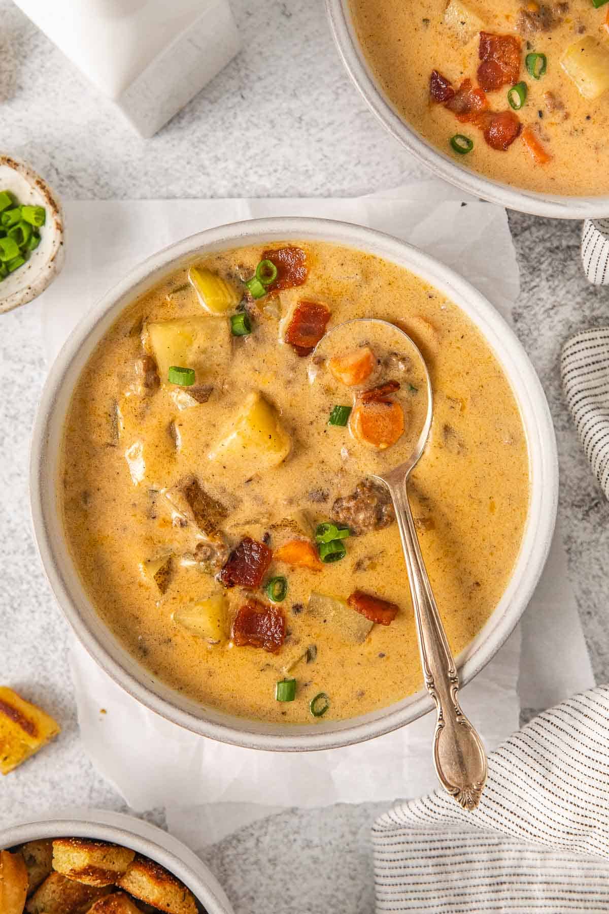 bowl full of creamy bacon cheeseburger soup with a spoon full leaning in the bowl.
