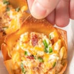closeup of a crispy jalapeno popper wonton cup being picked up by a womans fingers