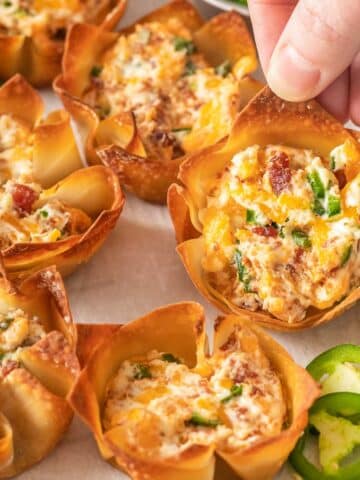 closeup of a wonton cup filled with cream cheese, bacon and jalapeno mixture.