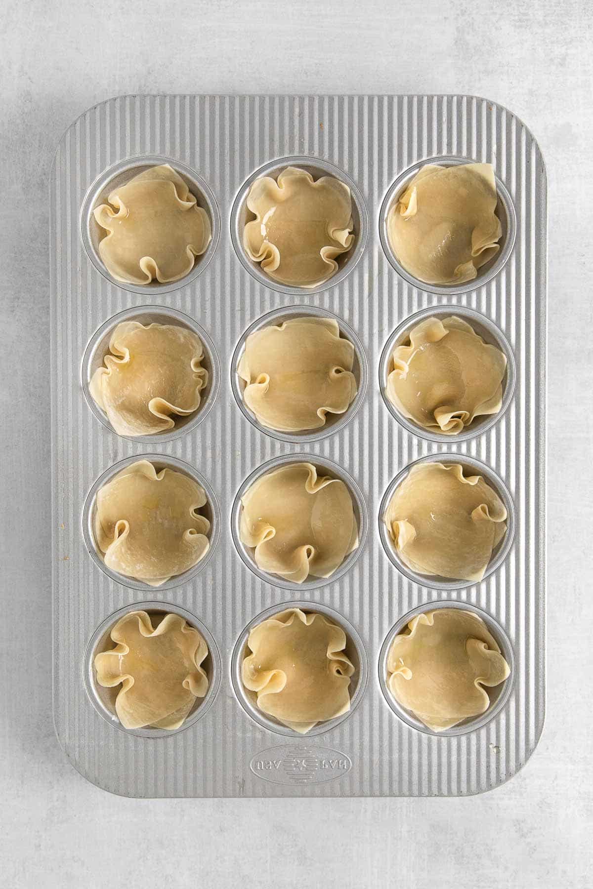 mini muffin tin with wonton wrappers in each hole.