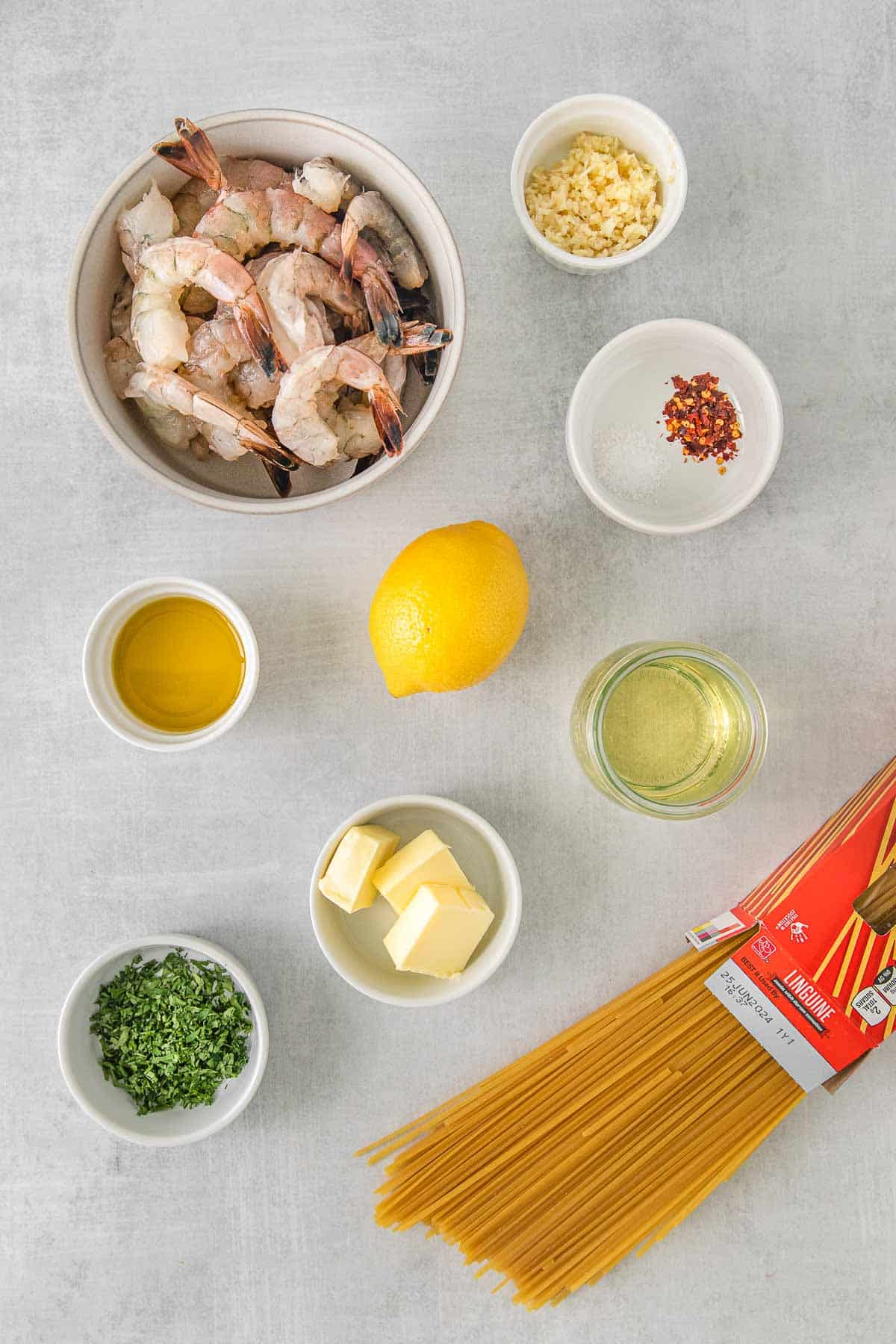 Ingredients for shrimp scampi - raw shrimp, butter, linguine noodles, parsley, lemon and oil.