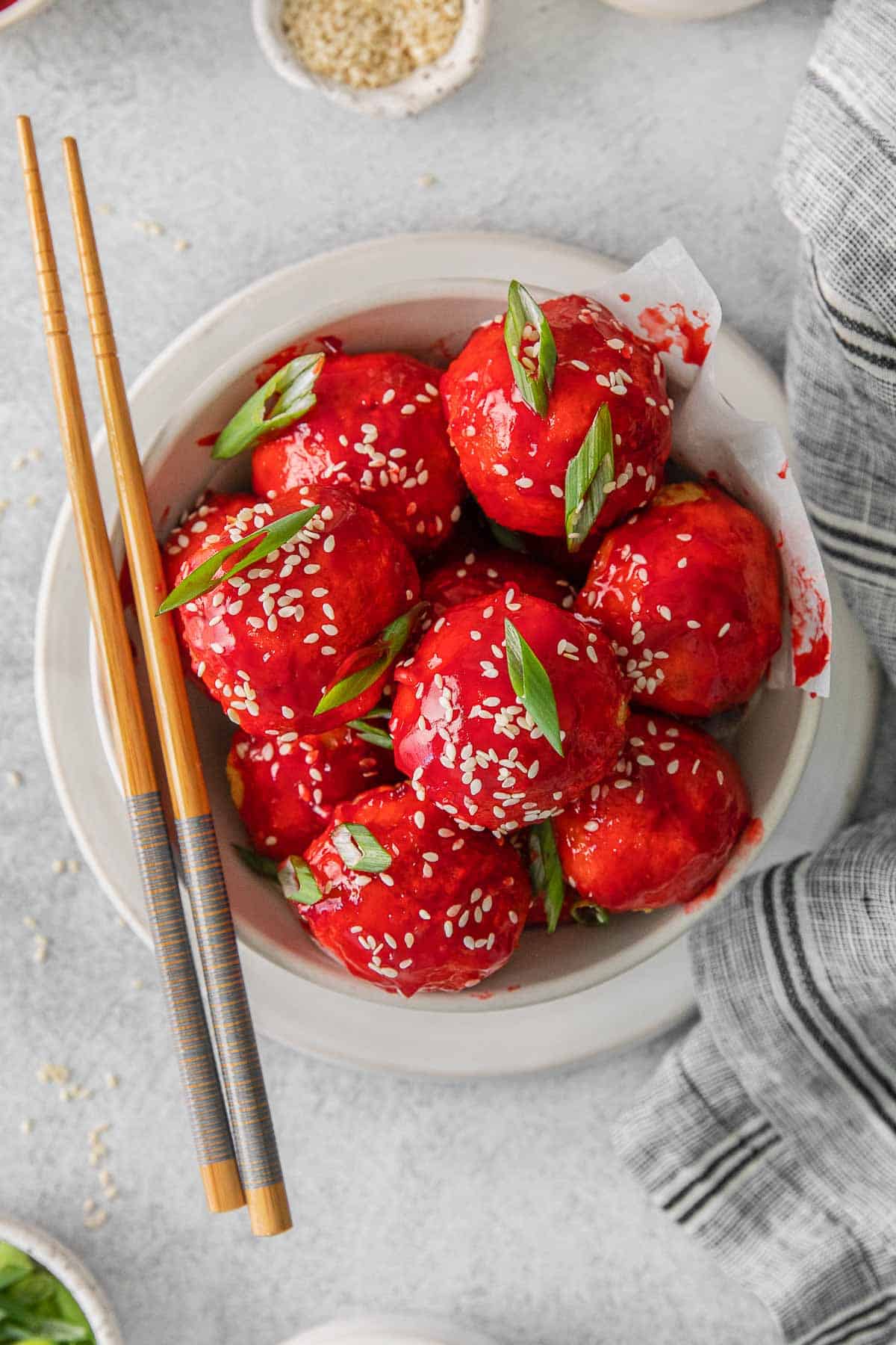 sweet and sour chicken meatballs in white bowl with chopsticks..