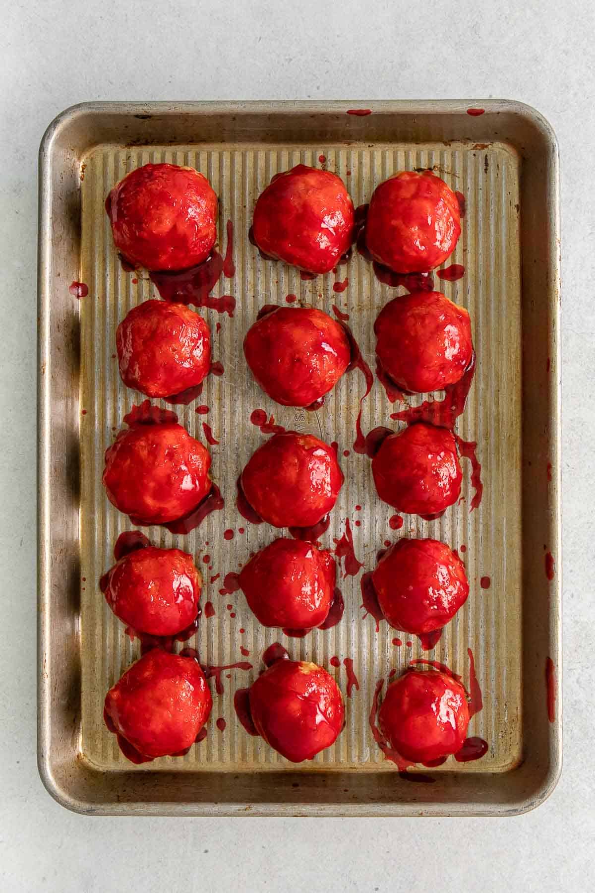 chicken meatballs brushed with sweet and sour glaze laid out on baking sheet.
