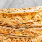 stack of four buffalo chicken quesadillas on a wood board.