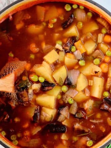 closeup of vegetable soup with diced potatoes in a tomato broth.