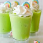 Close up of shot glass with green pudding topped with whipped cream and marshmallow.