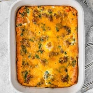 Breakfast casserole with sausage, egg and cheese in white rectangle baking dish.