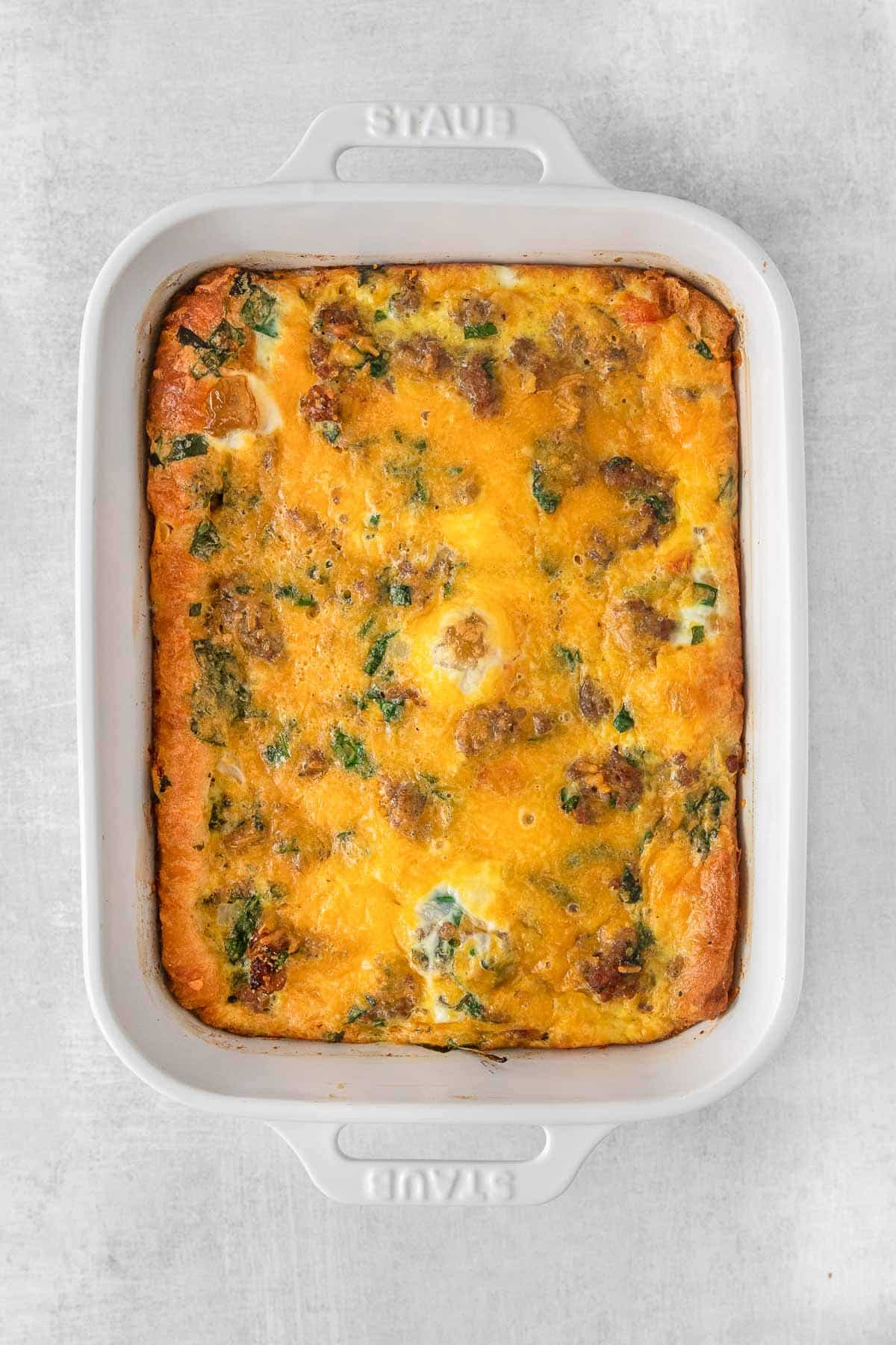 Breakfast casserole with sausage, egg and cheese in white rectangle baking dish.