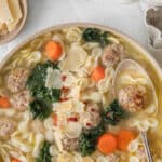 big white bowl full of classic Italian wedding soup with tiny meatballs and pasta with carrot and kale.