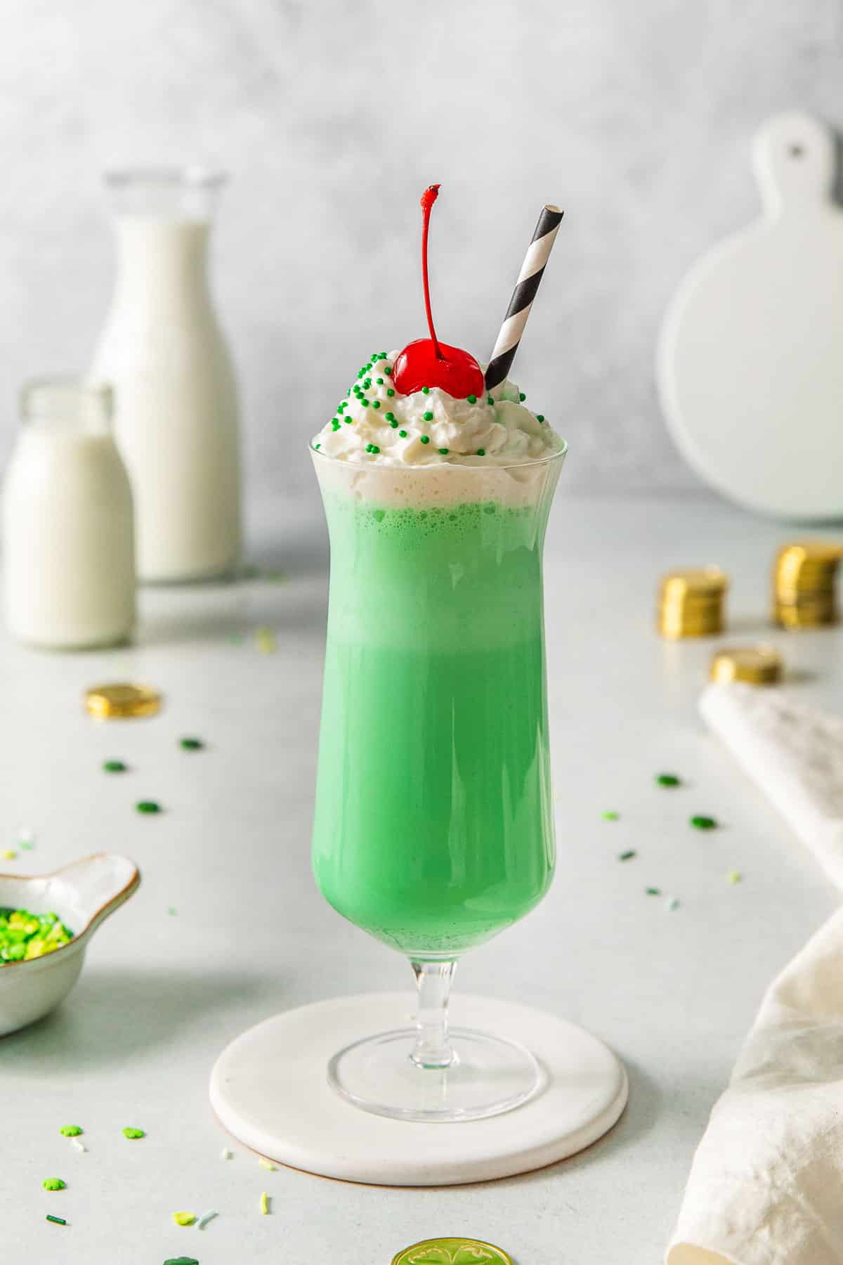 tall glass of shamrock shake topped with whipped cream and a cherry.