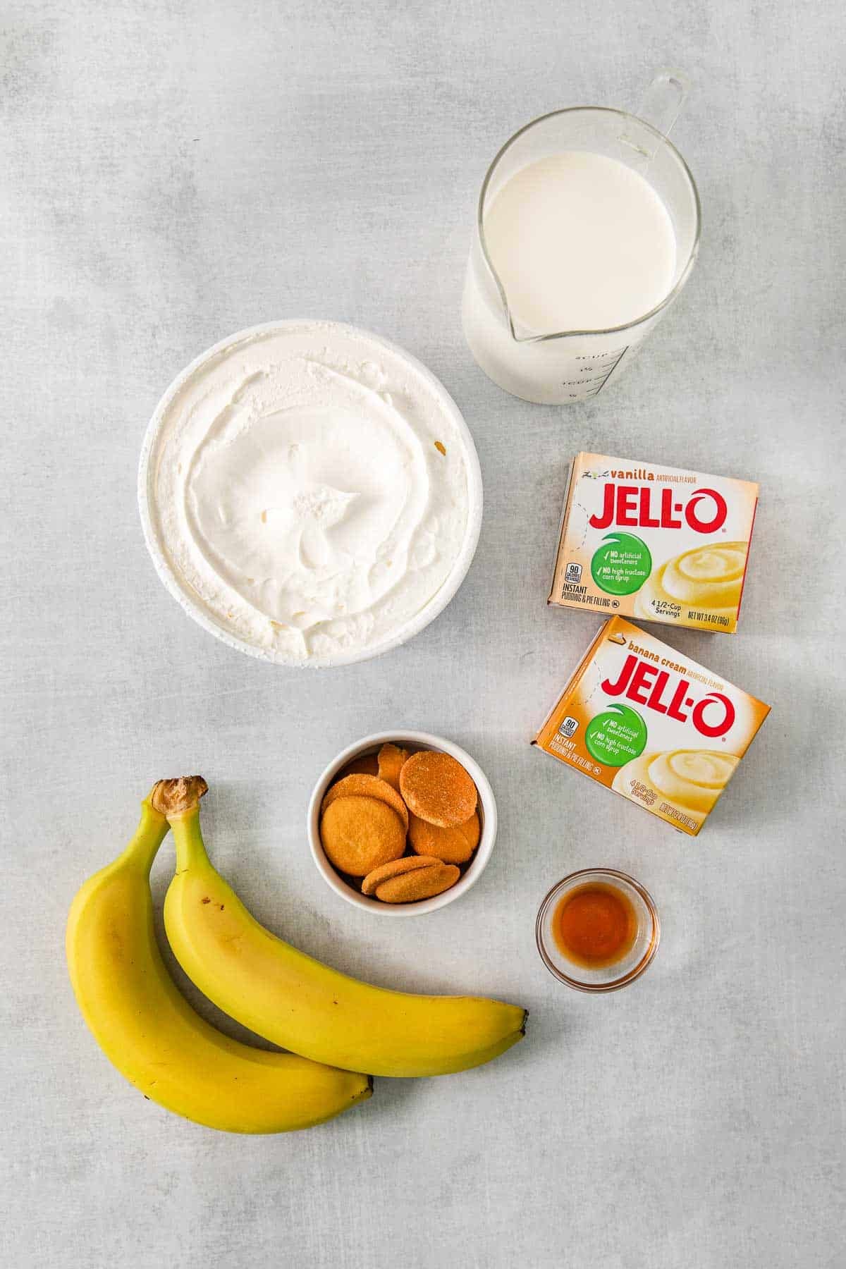 Several bowls with ingredients for Banana Pudding Pie - instant vanilla and banana pudding, half-and-half, bananas, cool whip, vanilla extract and nilla wafers.