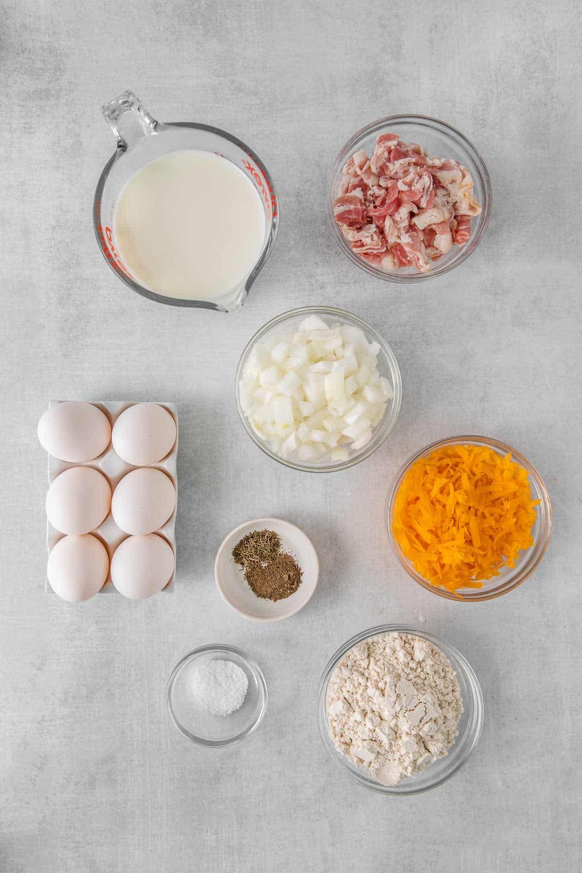 Several bowls with ingredients for Bisquick Quiche - Bacon, Onion, Milk, Bisquick mix, Eggs, Salt, Black Pepper, Thyme and Cheddar Cheese.