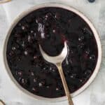 Blueberry sauce in a bowl with a spoon.
