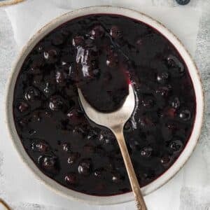 Blueberry sauce in a bowl with a spoon.