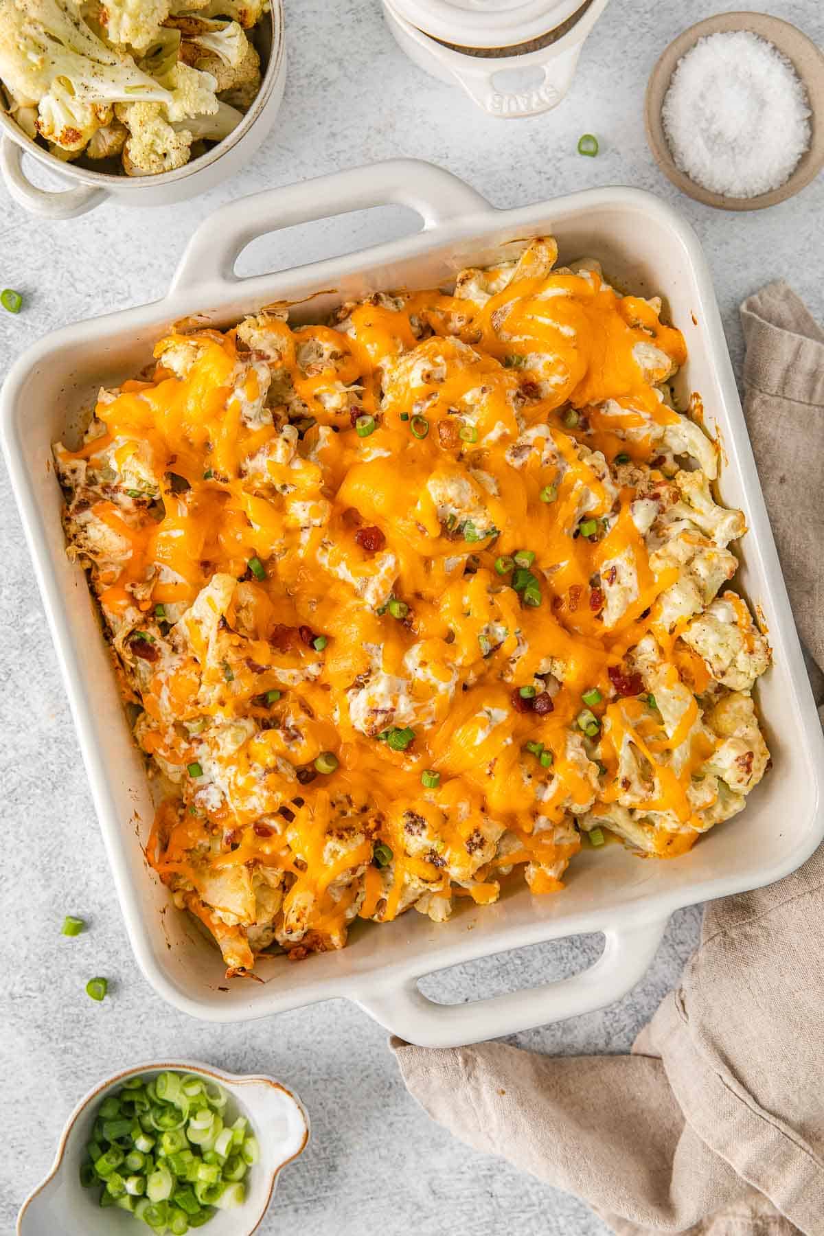 Cheesy cauliflower casserole in white baking dish.