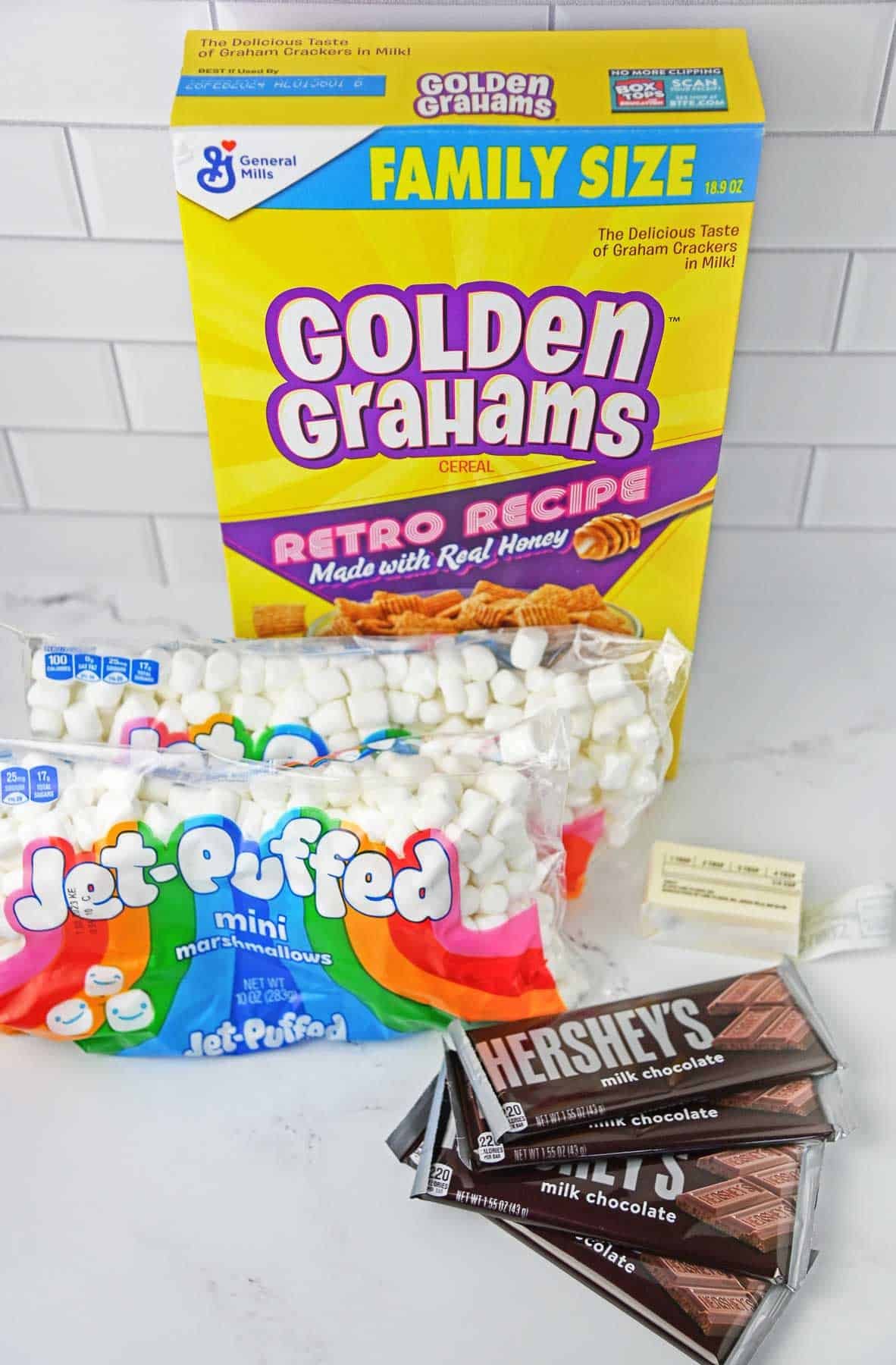 Ingredients for Golden Graham cereal bars - marshmallows, golden grahams cereal, butter and chocolate bars.